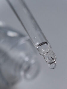 A clear dropper with a drop of water coming out